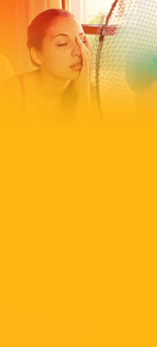 Woman cooling off in front of a fan in a warm room