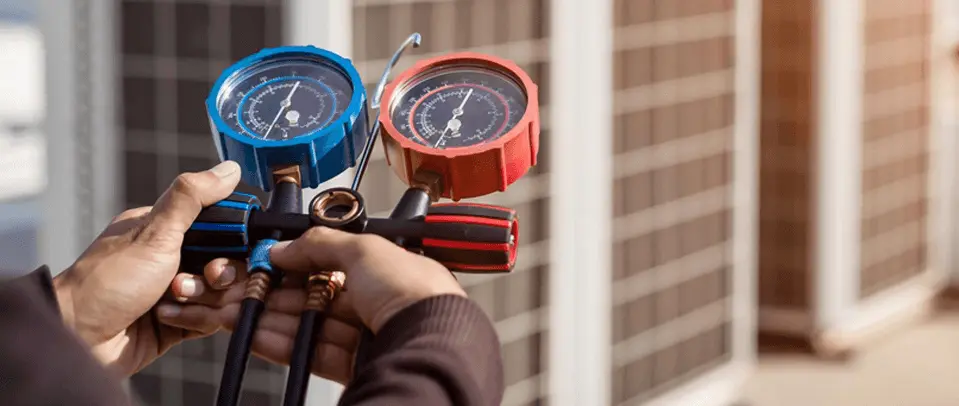 Technician holding HVAC refrigerant manifold gauges